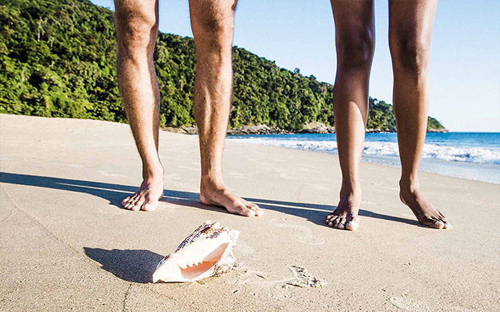 Primo piano della gambe di due persone su una spiaggia tropicale